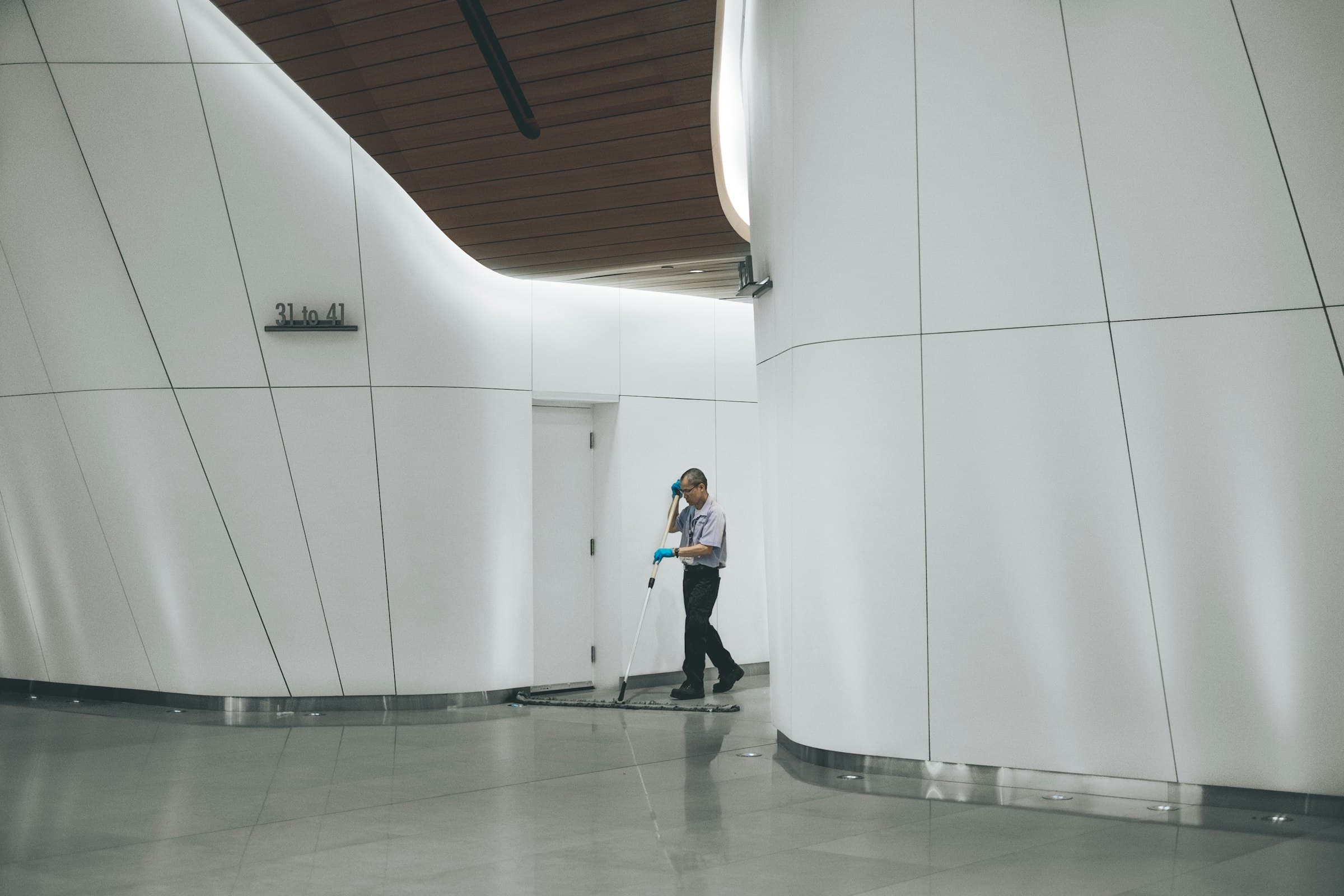 Person bei der Bodenreinigung mit einem Wischmopp in einem hellen Flur – Symbolbild